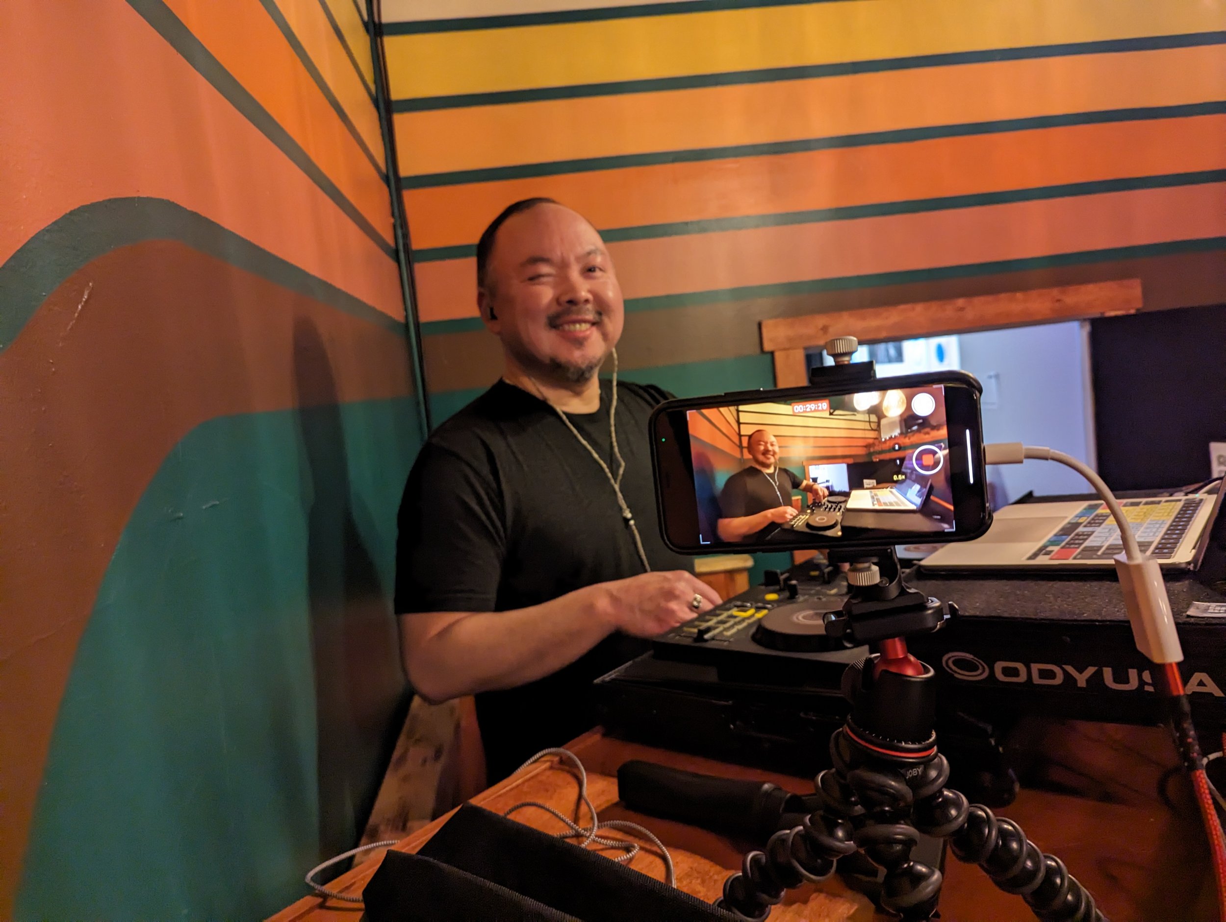 Sang-Do playing a live set with a smartphone camera mounted on a flexible tripod.