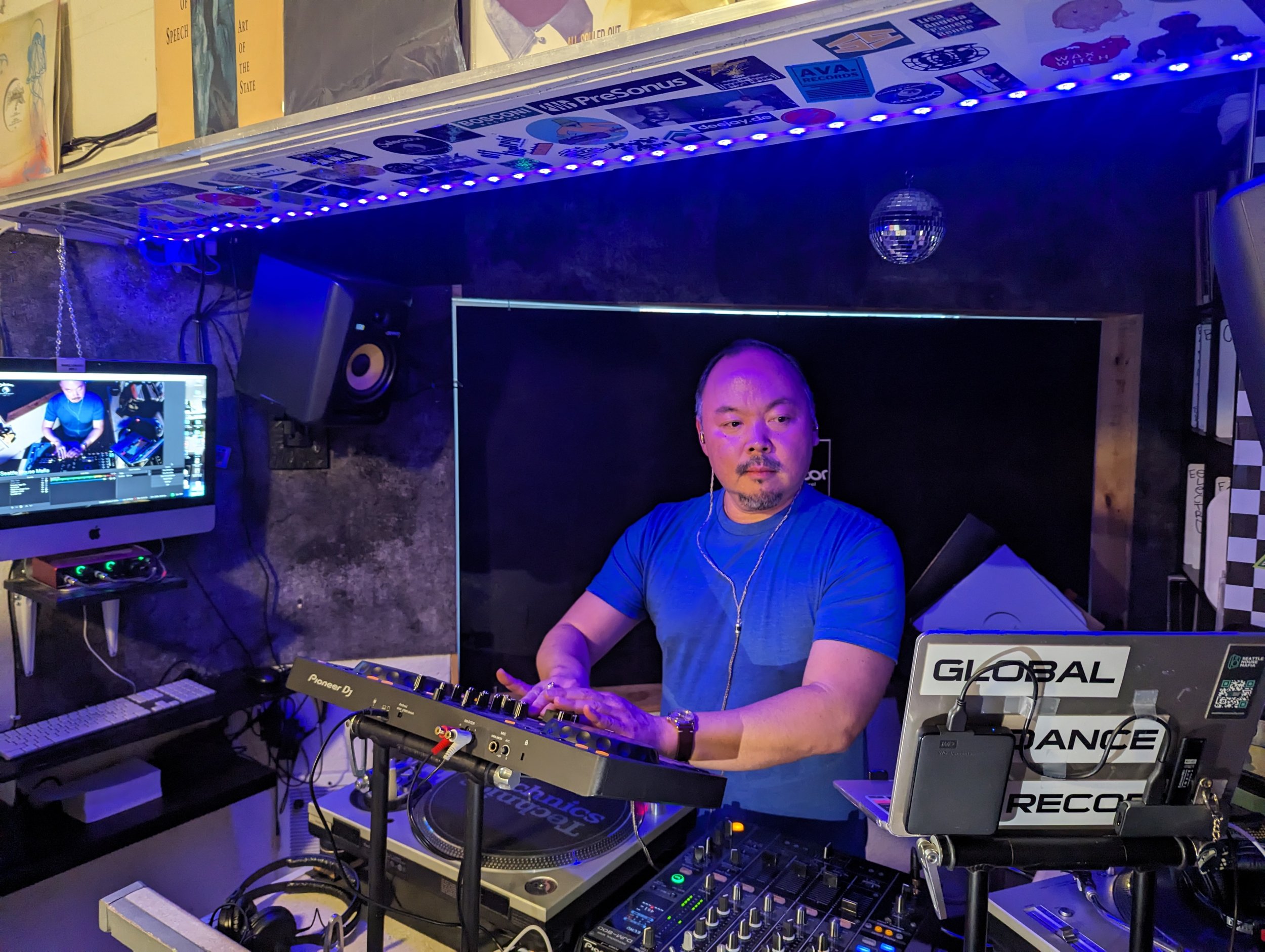 Sang-Do at a professionally lit studio setup with Pioneer DJ equipment and Global Dance Records branding.