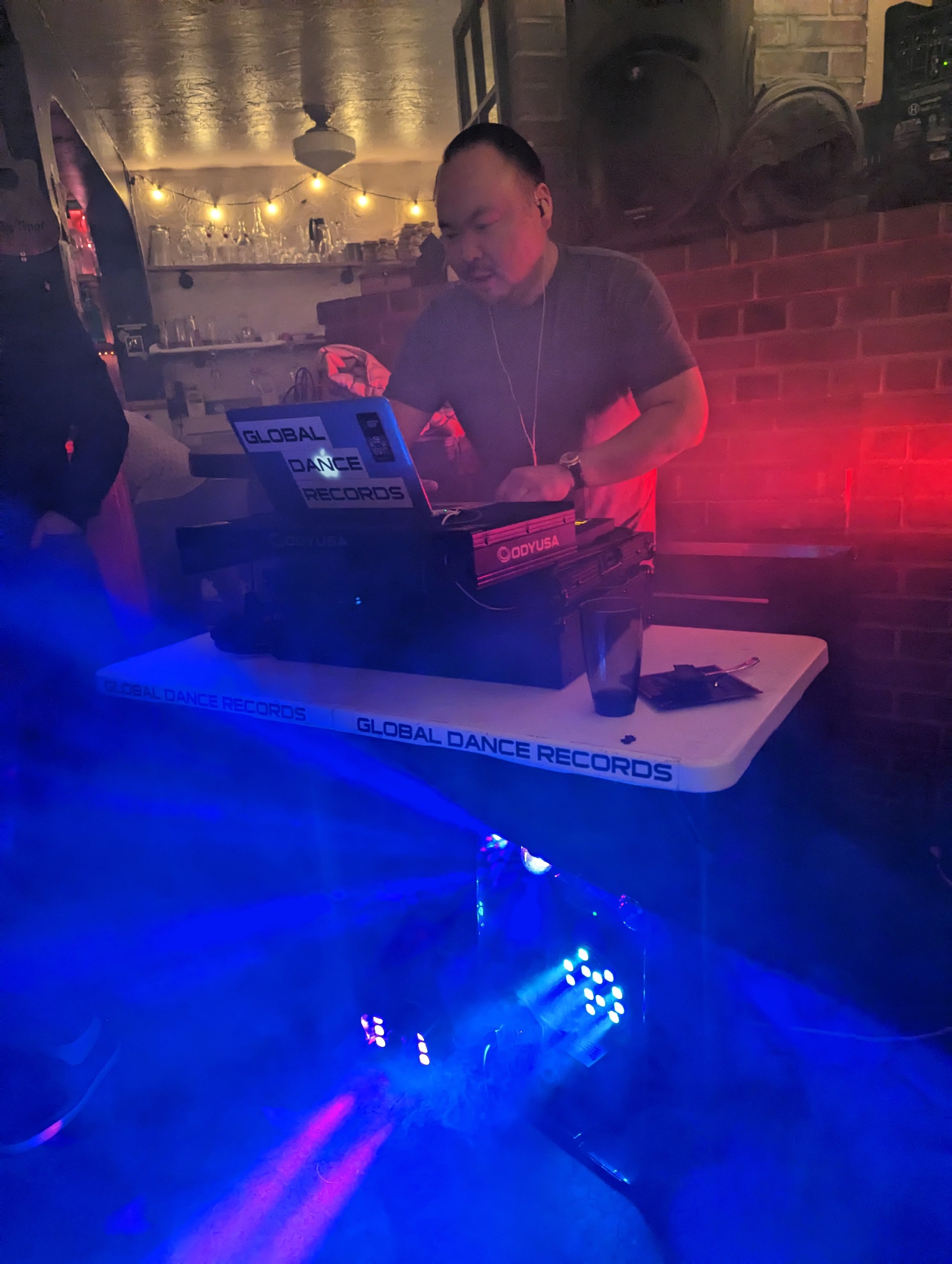 DJ booth at Global Dance Records with neon blue lighting and extensive vinyl record collection visible
