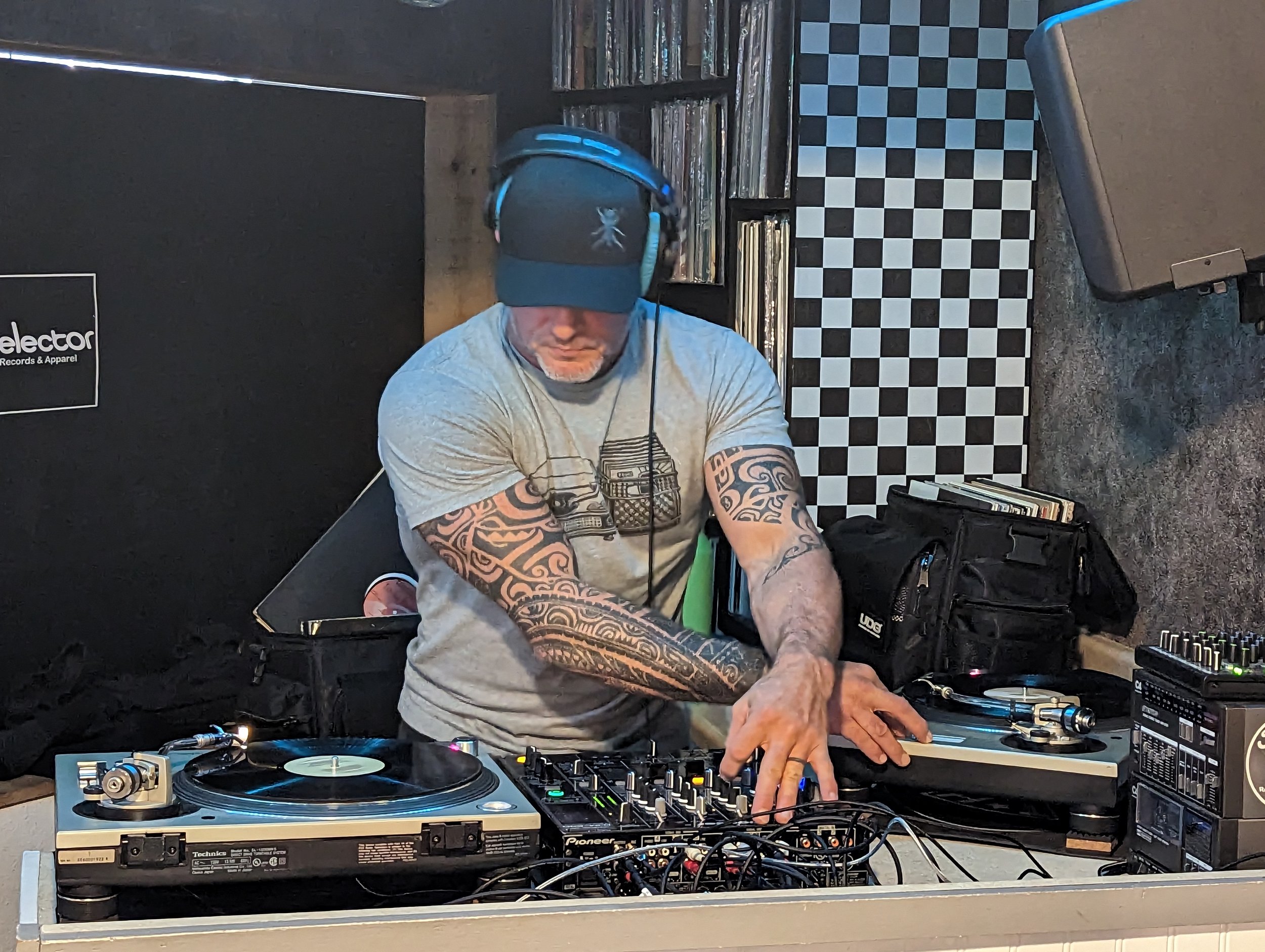 DJ focused on mixing at night club with Pioneer DJ equipment in dark lighting with blue accent lights