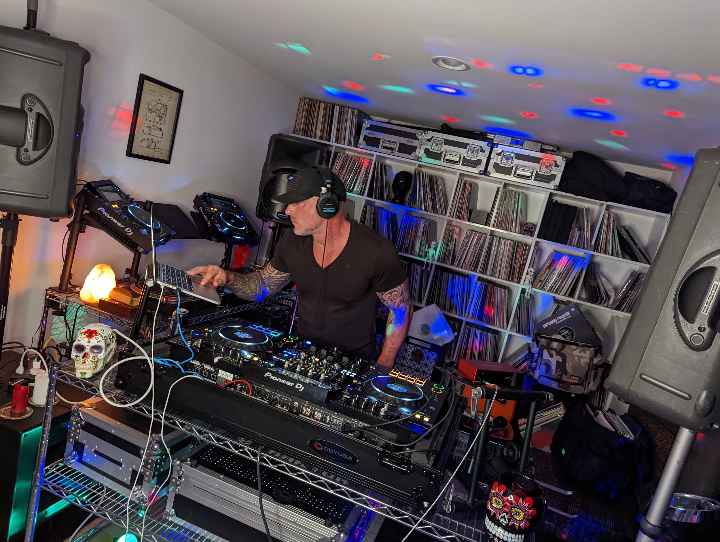 Crowd dancing at a nightclub with DJ booth decorated with purple flower garlands