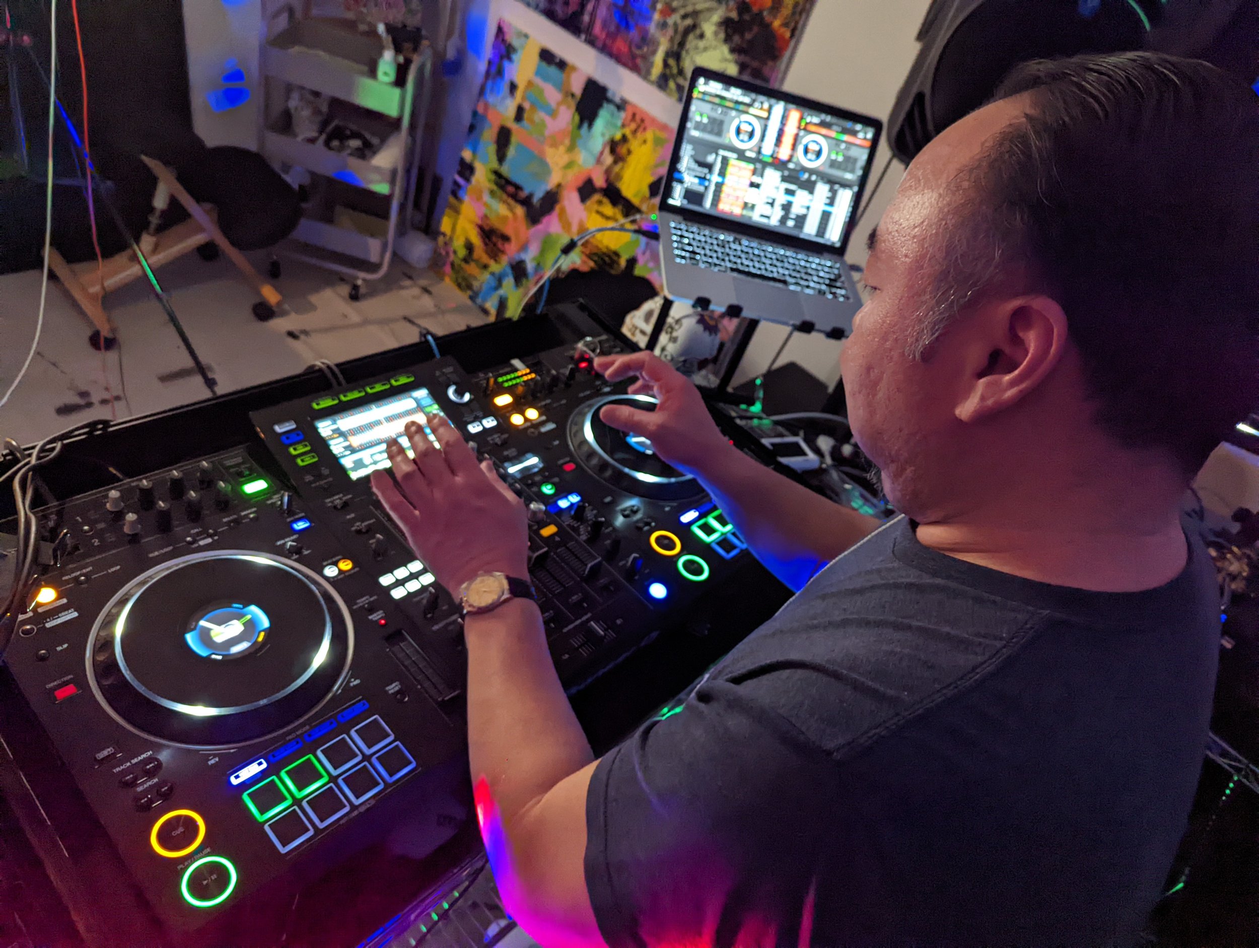 DJ performing at a club with glowing Pioneer CDJ displays and green accent lighting