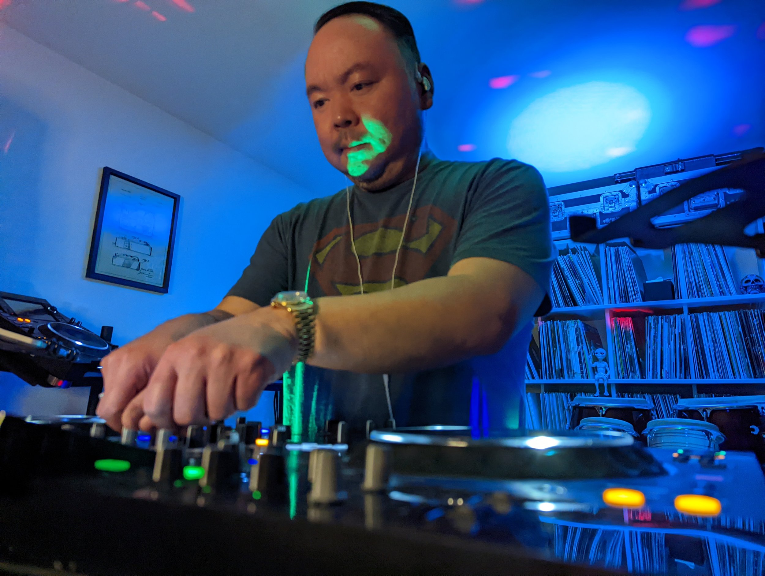 DJ performing with red lighting and crowd in background, focused on Pioneer mixer