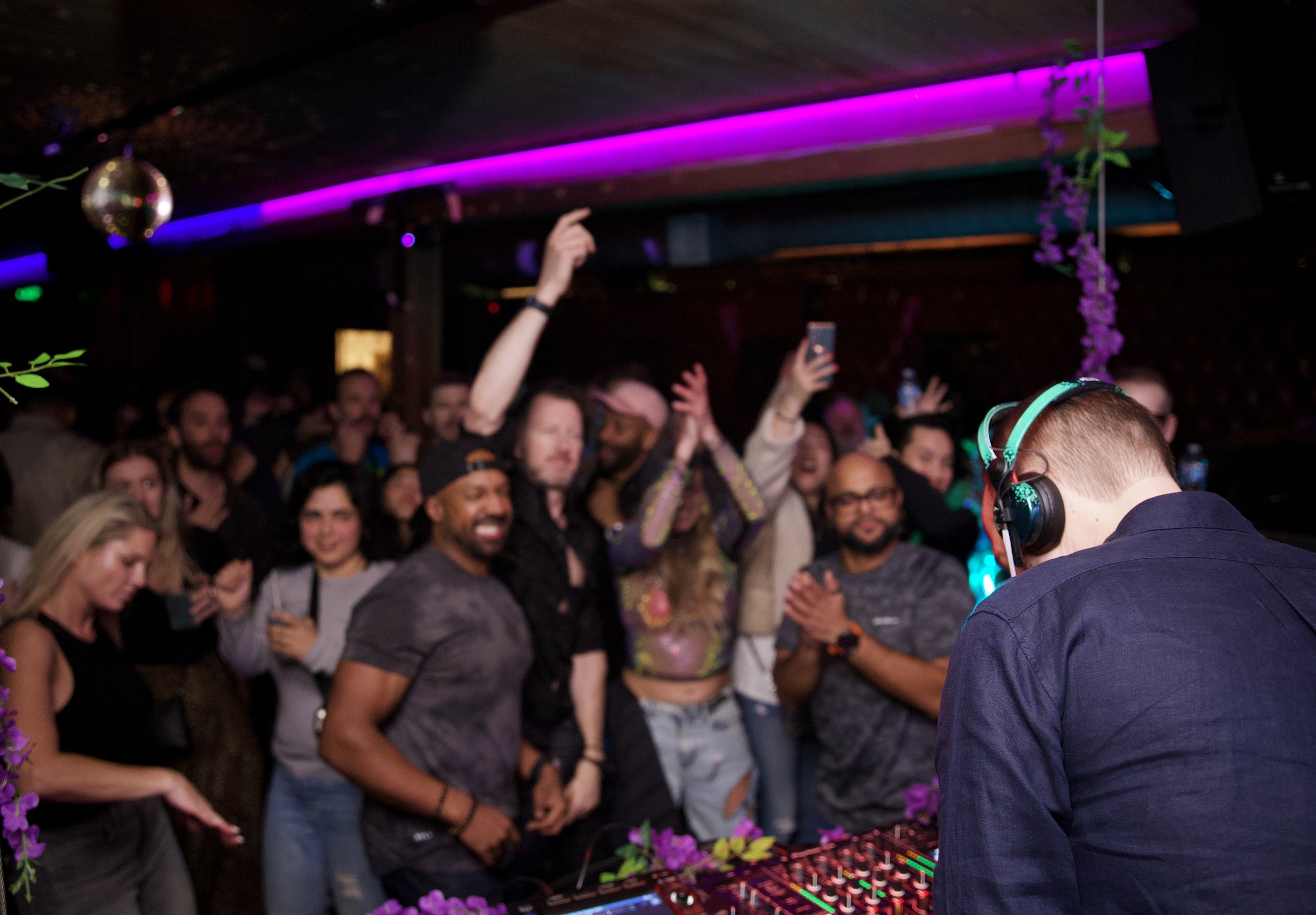 Black and white photo of DJ performing with raised hands in the crowd