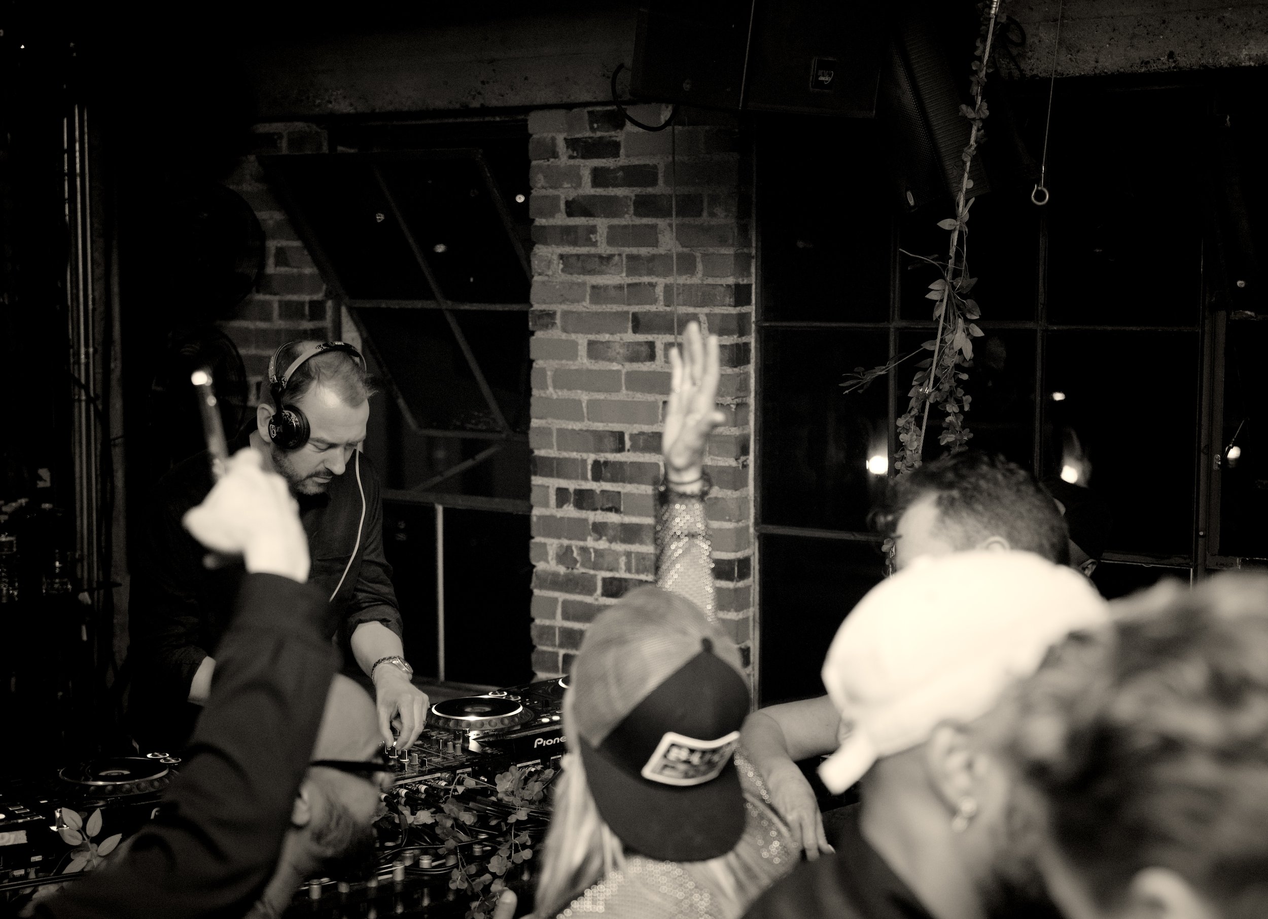 Packed dance floor with DJ booth visible and colorful lighting