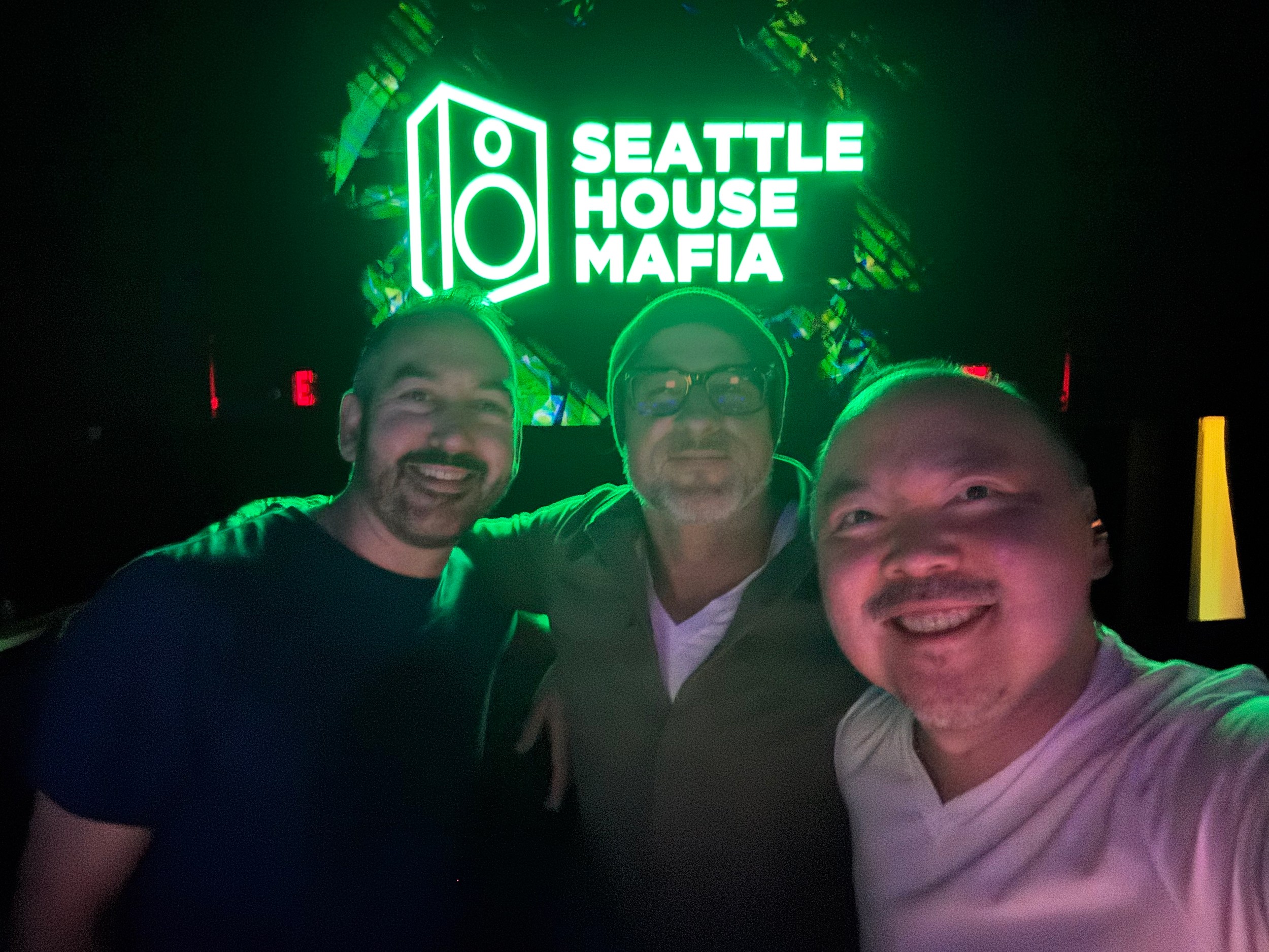 The Seattle House Mafia trio together in front of their green neon sign at Q Nightclub