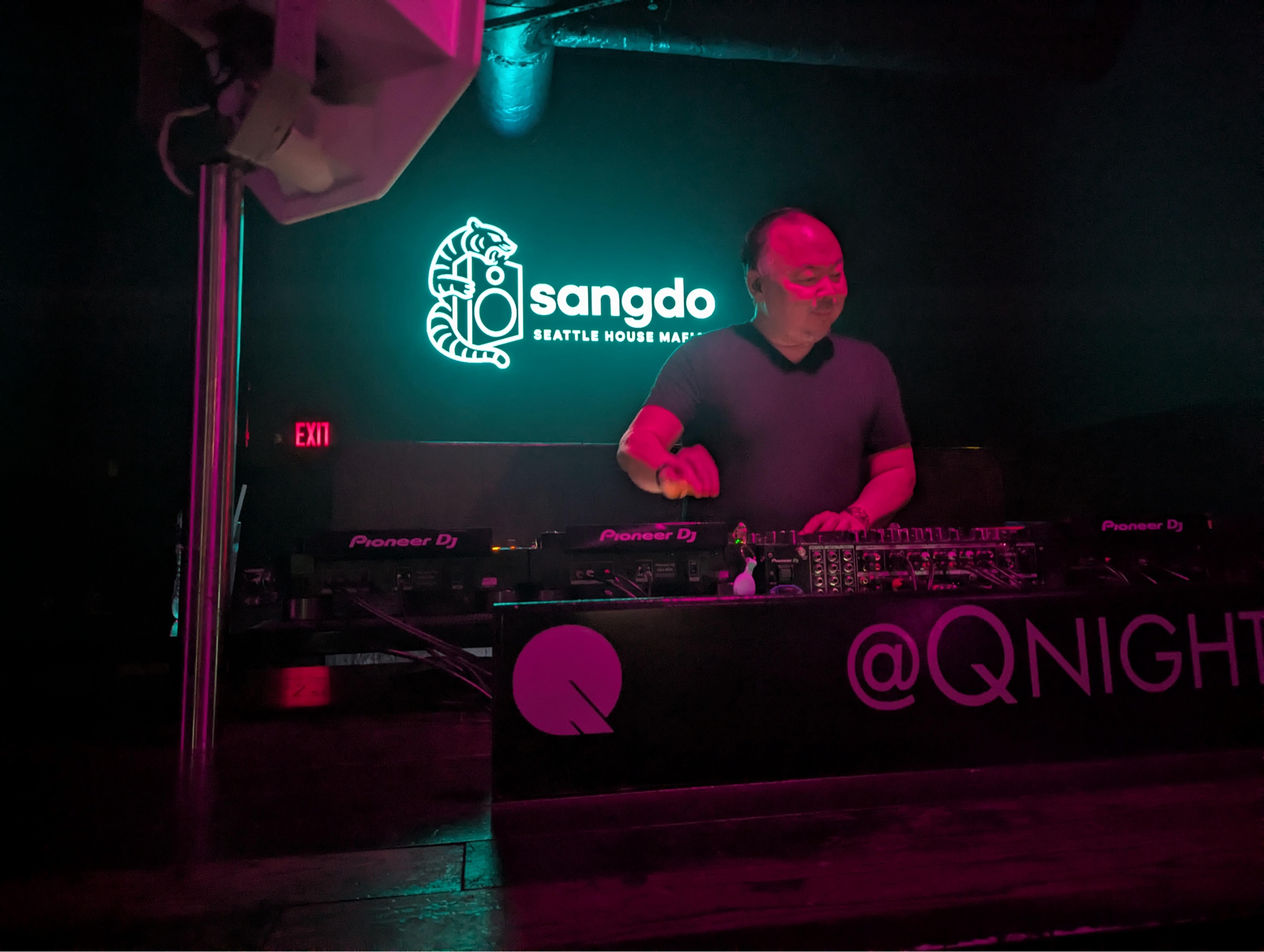 DJ sangdo performing at Q Nightclub beneath his illuminated Seattle House Mafia sign