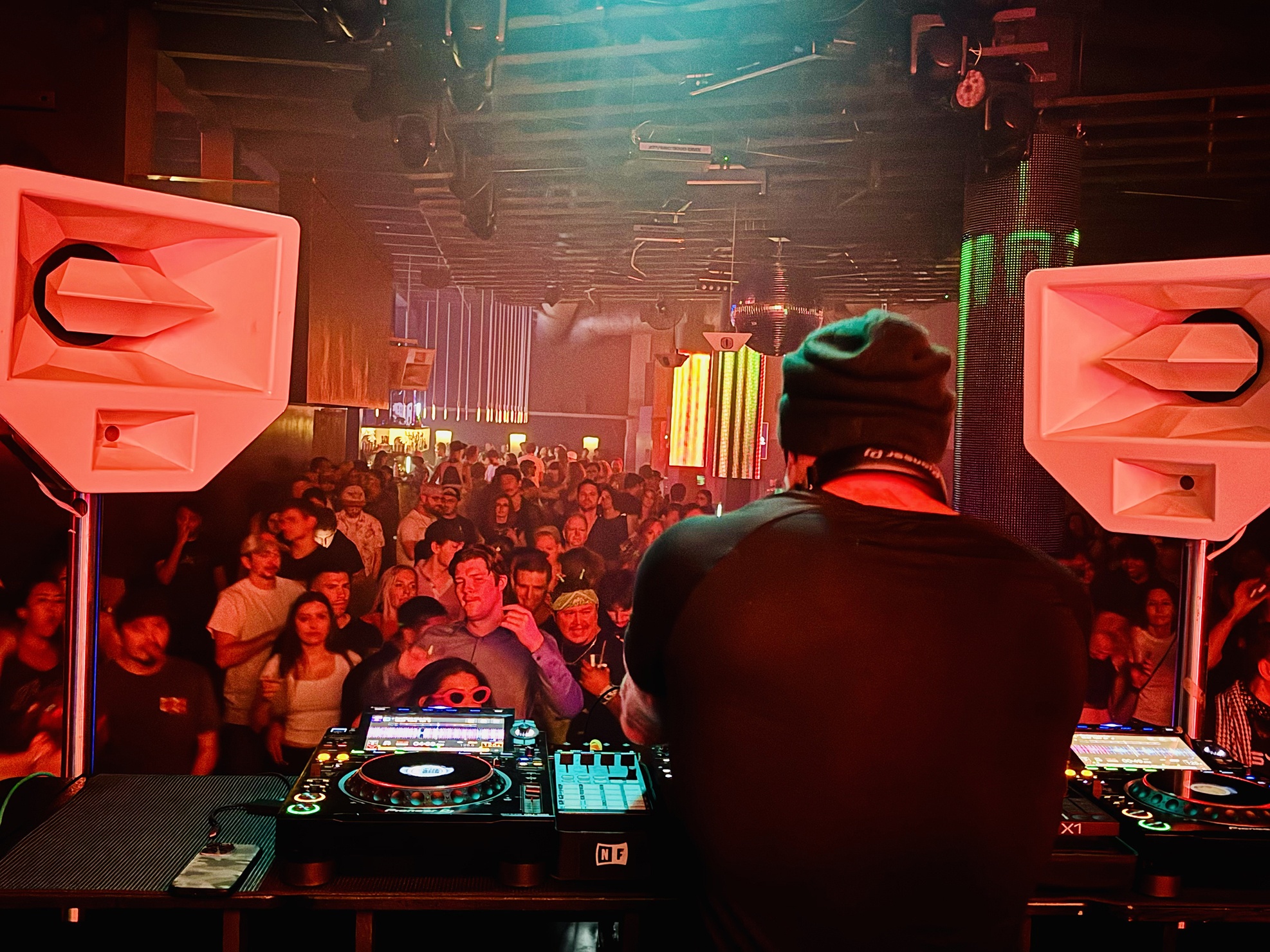 Phil Anthony DJing at Q Nightclub, shot from behind the shoulder with a view of a packed dancefloor crowd